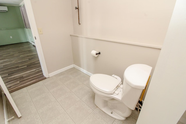 bathroom featuring toilet, baseboards, and a wall mounted air conditioner