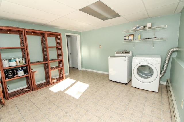 clothes washing area featuring a baseboard heating unit, washing machine and dryer, laundry area, and baseboards