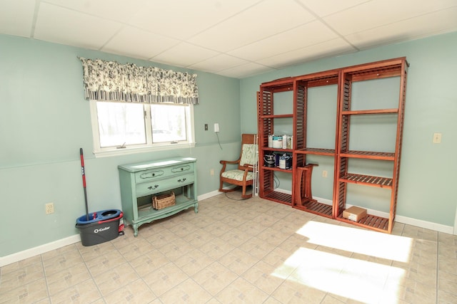 sitting room featuring a drop ceiling and baseboards