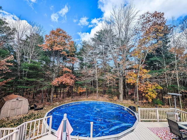 view of pool featuring an outdoor structure, a deck, and a storage shed