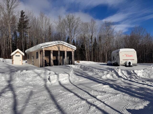 exterior space with a storage shed, an outdoor structure, and a view of trees