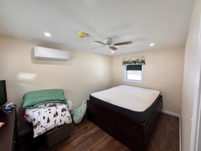 bedroom with ceiling fan, recessed lighting, wood finished floors, baseboards, and a wall mounted AC