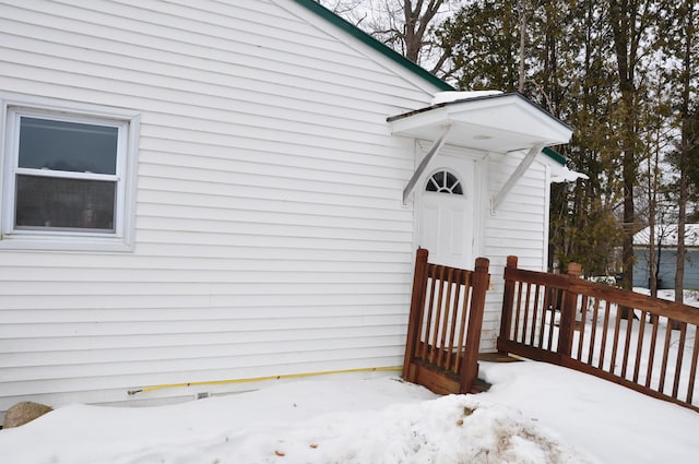 snow covered property entrance with crawl space