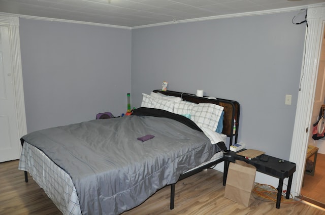 bedroom with crown molding and wood finished floors