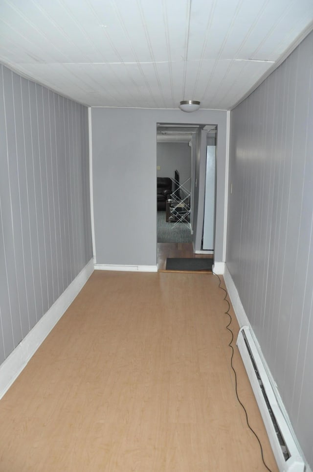 unfurnished room featuring a baseboard heating unit, baseboards, and wood finished floors