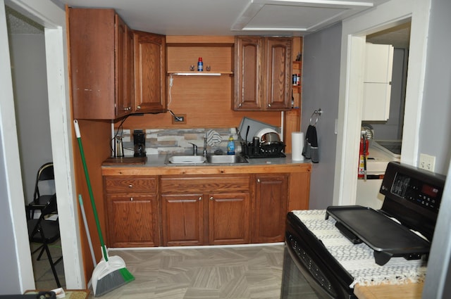 kitchen with a sink, brown cabinets, tasteful backsplash, and light countertops