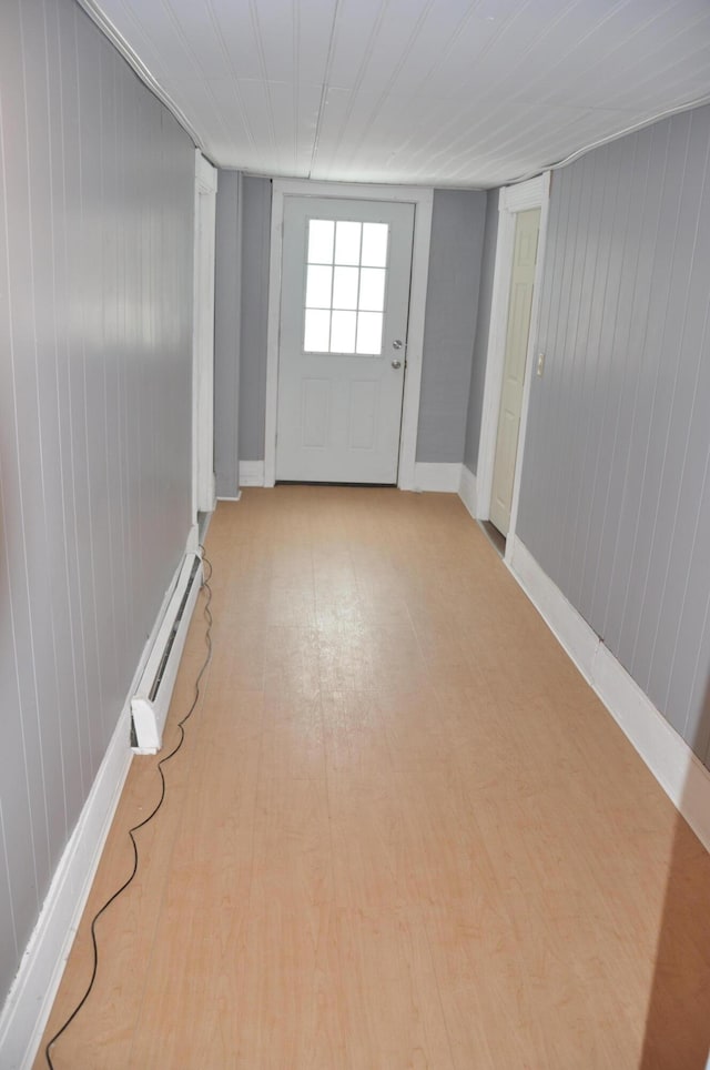spare room with a baseboard heating unit, baseboards, and light wood-style floors