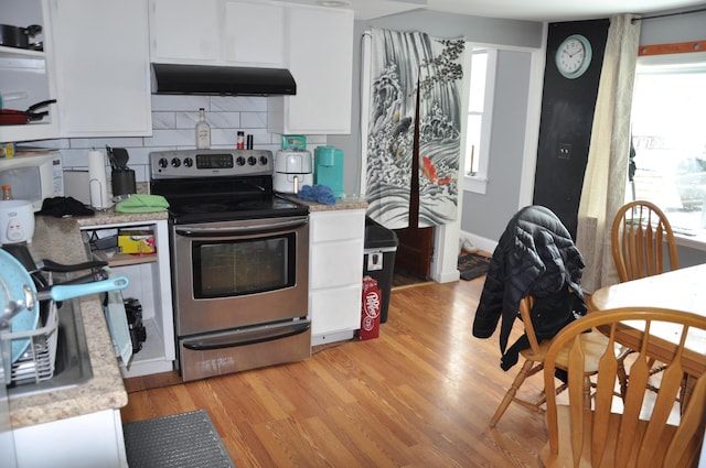 kitchen with white microwave, light wood finished floors, extractor fan, stainless steel range with electric cooktop, and white cabinets