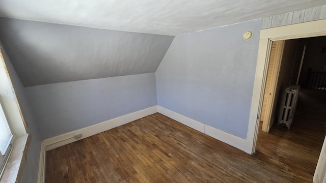 additional living space with lofted ceiling, radiator heating unit, dark wood finished floors, and baseboards