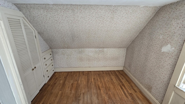 bonus room featuring dark wood-type flooring, vaulted ceiling, baseboards, and wallpapered walls