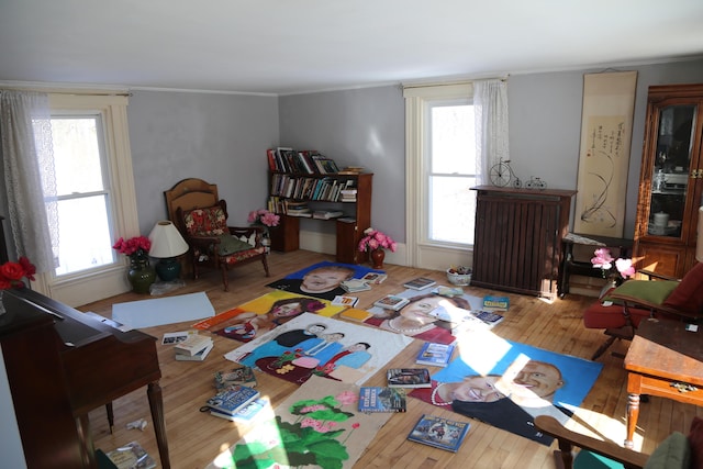 game room featuring a healthy amount of sunlight, ornamental molding, and wood finished floors