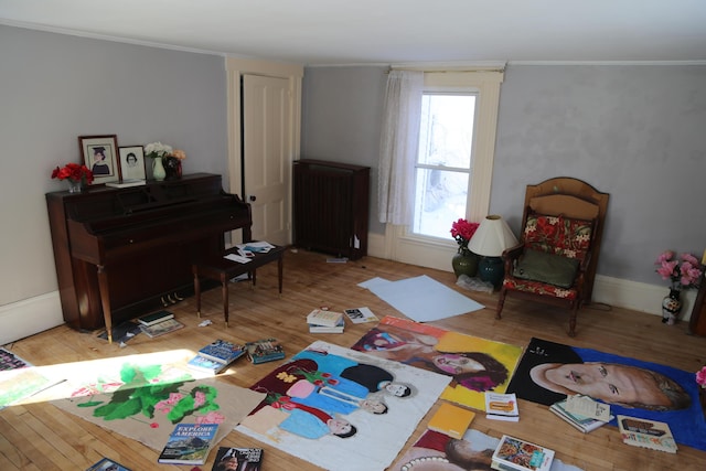 interior space featuring ornamental molding, radiator, baseboards, and wood finished floors