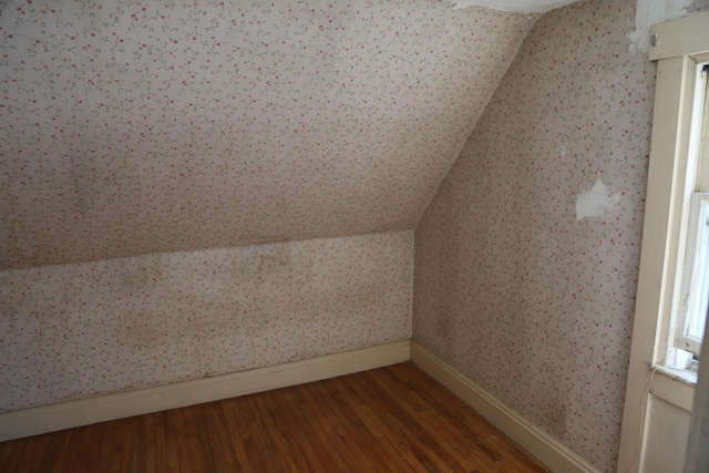 bonus room featuring lofted ceiling, baseboards, wood finished floors, and wallpapered walls