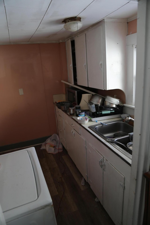 kitchen featuring washer / dryer, dark wood finished floors, and a sink