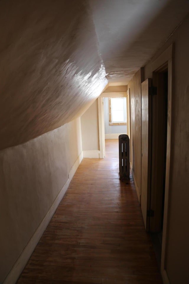 additional living space featuring lofted ceiling, dark wood-style flooring, and baseboards