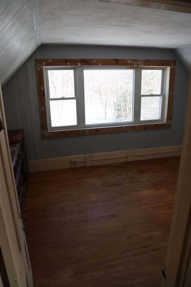 additional living space featuring dark wood-style floors, vaulted ceiling, and baseboards