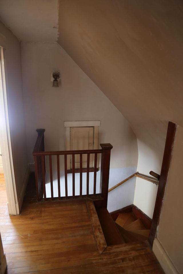 stairway with lofted ceiling, baseboards, and wood finished floors