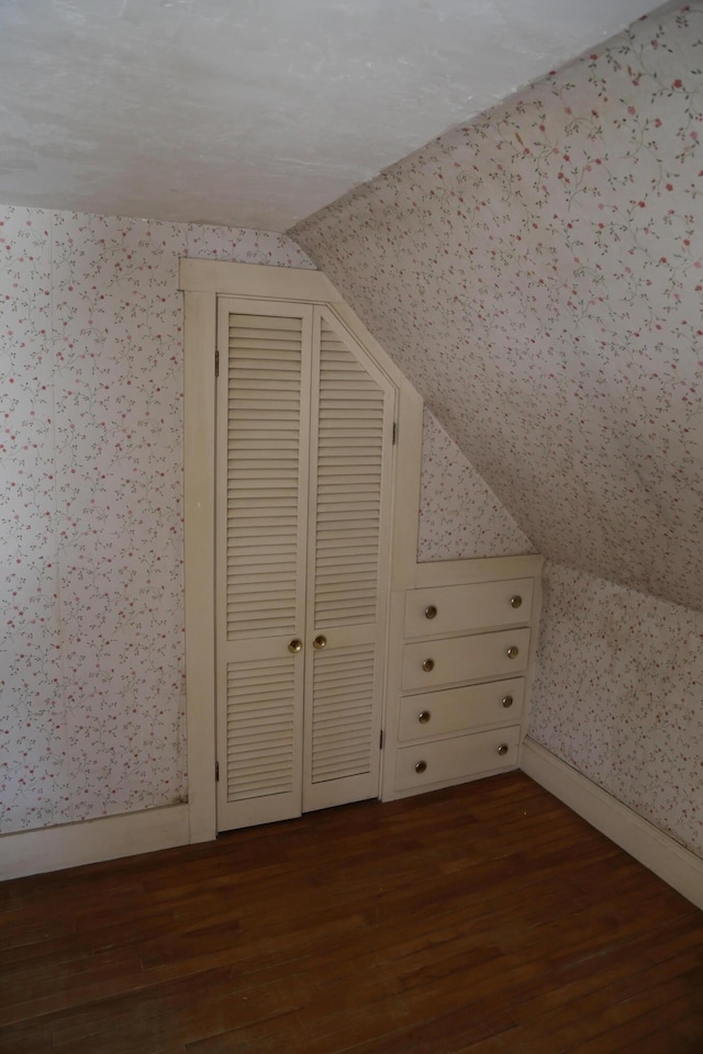 additional living space with lofted ceiling, dark wood-style floors, and wallpapered walls