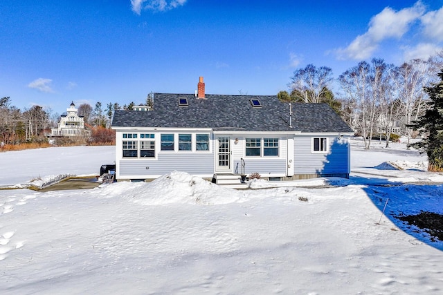 snow covered rear of property featuring a chimney