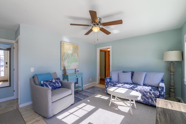 living room featuring light wood-type flooring, baseboards, and a ceiling fan
