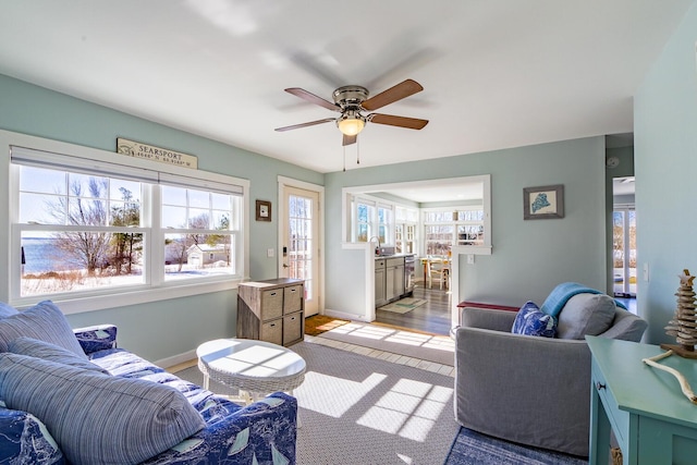 living area with ceiling fan, baseboards, and a healthy amount of sunlight