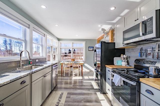 kitchen featuring recessed lighting, backsplash, light wood-style flooring, appliances with stainless steel finishes, and a sink