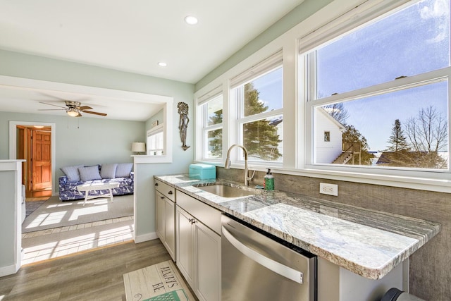kitchen featuring light stone counters, recessed lighting, stainless steel dishwasher, a sink, and light wood-type flooring