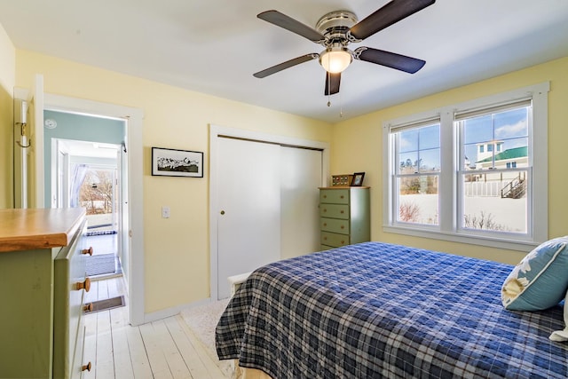 bedroom with light wood-style flooring, baseboards, ceiling fan, and a closet
