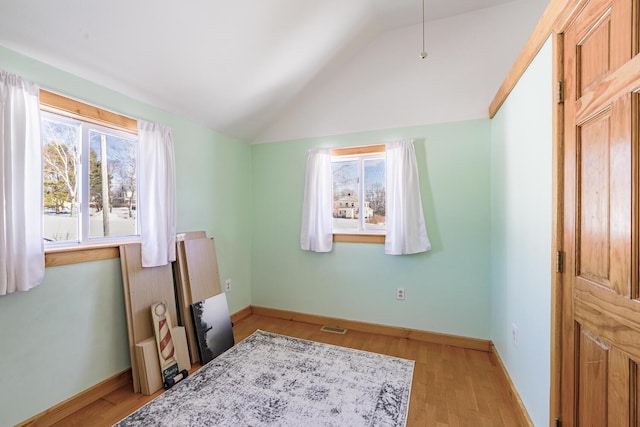 bedroom with lofted ceiling, visible vents, light wood-style flooring, and baseboards