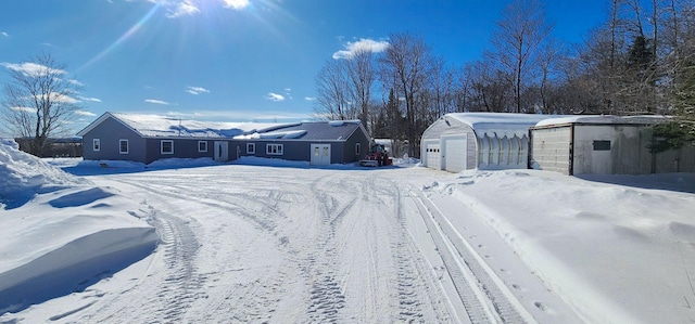 yard layered in snow featuring an outbuilding and a garage