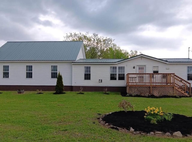 back of property featuring metal roof, a yard, and a wooden deck