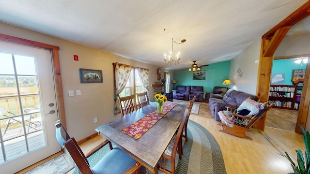 dining space with lofted ceiling, wood finished floors, and a notable chandelier