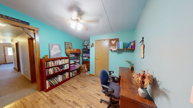 office area featuring vaulted ceiling, light wood-type flooring, a ceiling fan, and baseboards