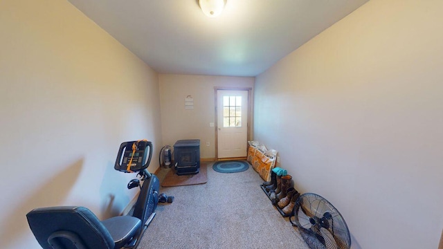 workout room featuring carpet and a wood stove