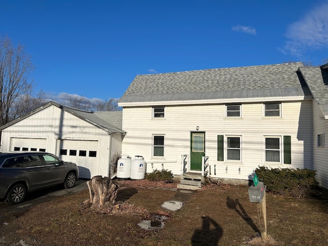 colonial house featuring entry steps, a shingled roof, and an attached garage