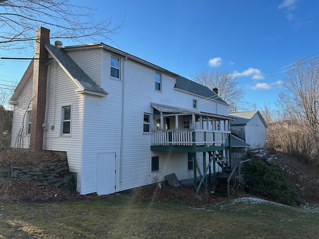 back of house with a deck, a yard, a chimney, and roof with shingles