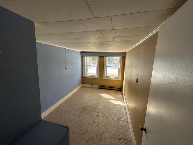 carpeted empty room with a baseboard radiator and baseboards