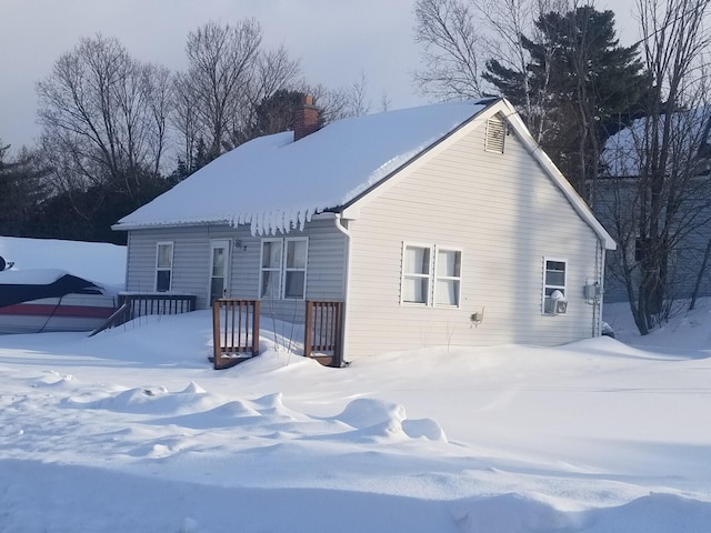 snow covered back of property featuring a chimney