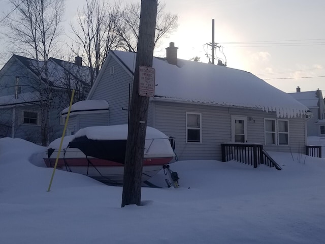 snow covered house featuring a chimney