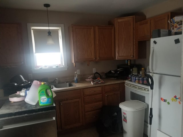 kitchen featuring a sink, light countertops, freestanding refrigerator, brown cabinetry, and decorative light fixtures