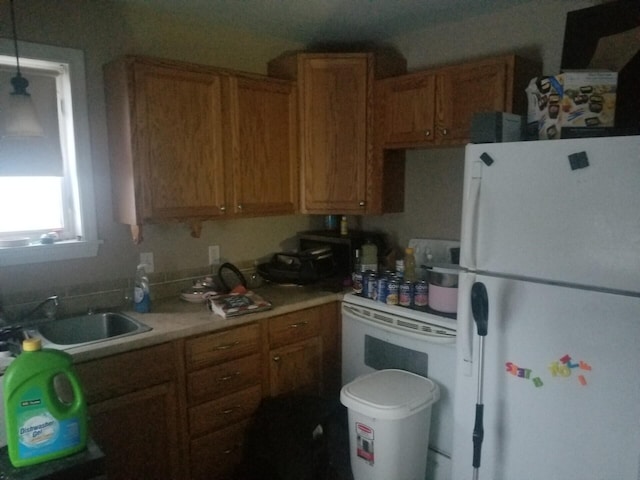 kitchen featuring brown cabinets, white appliances, light countertops, and a sink