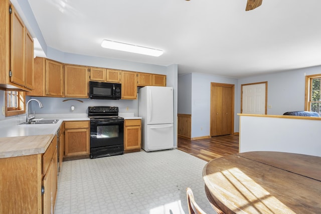 kitchen with black appliances, light countertops, a sink, and light floors