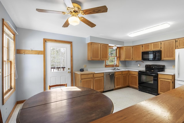 kitchen with light countertops, a ceiling fan, a sink, black appliances, and baseboards