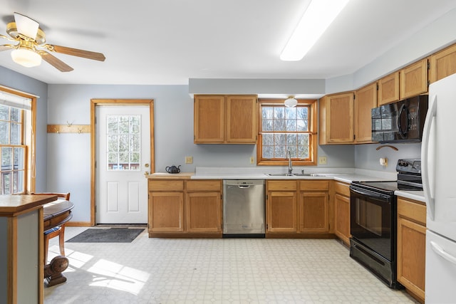 kitchen featuring plenty of natural light, light floors, light countertops, black appliances, and a sink