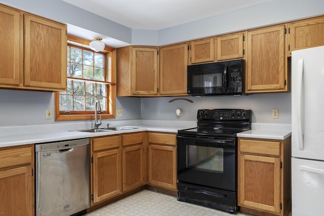 kitchen with black appliances, light countertops, a sink, and light floors