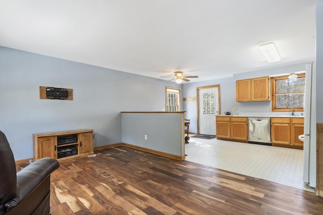 kitchen with a sink, dark wood-type flooring, light countertops, and stainless steel dishwasher