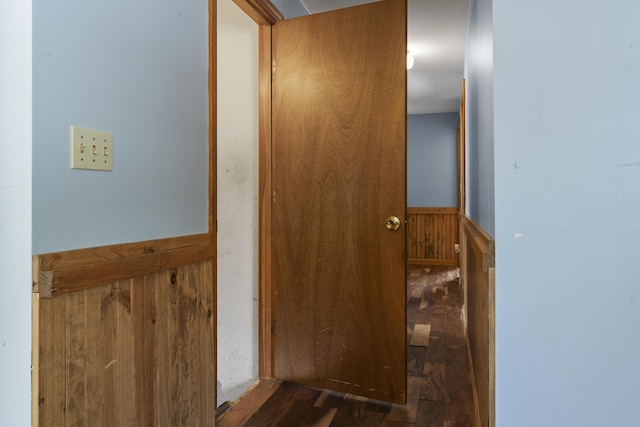 corridor featuring wainscoting and wooden walls