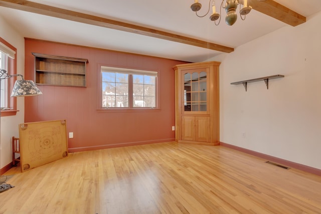 empty room featuring light wood-type flooring, beam ceiling, visible vents, and an inviting chandelier