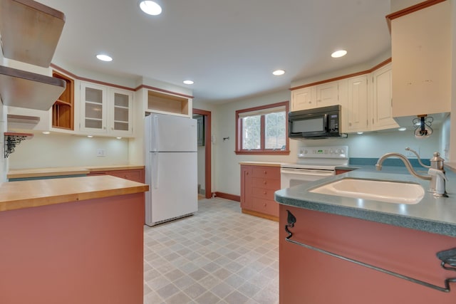 kitchen with white appliances, a sink, glass insert cabinets, and recessed lighting