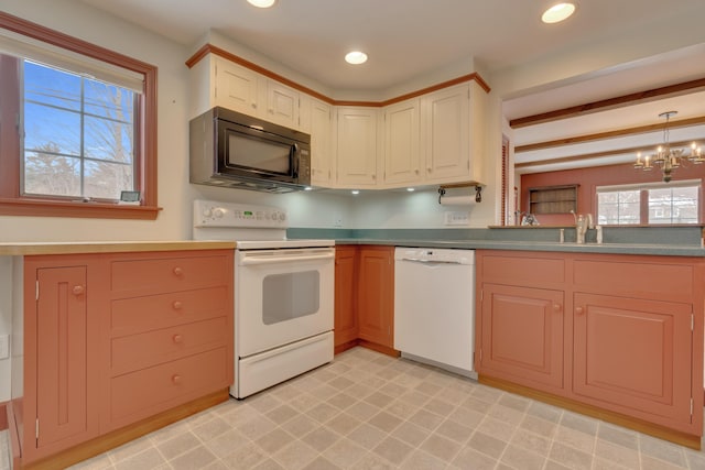 kitchen featuring white appliances, plenty of natural light, decorative light fixtures, and a notable chandelier